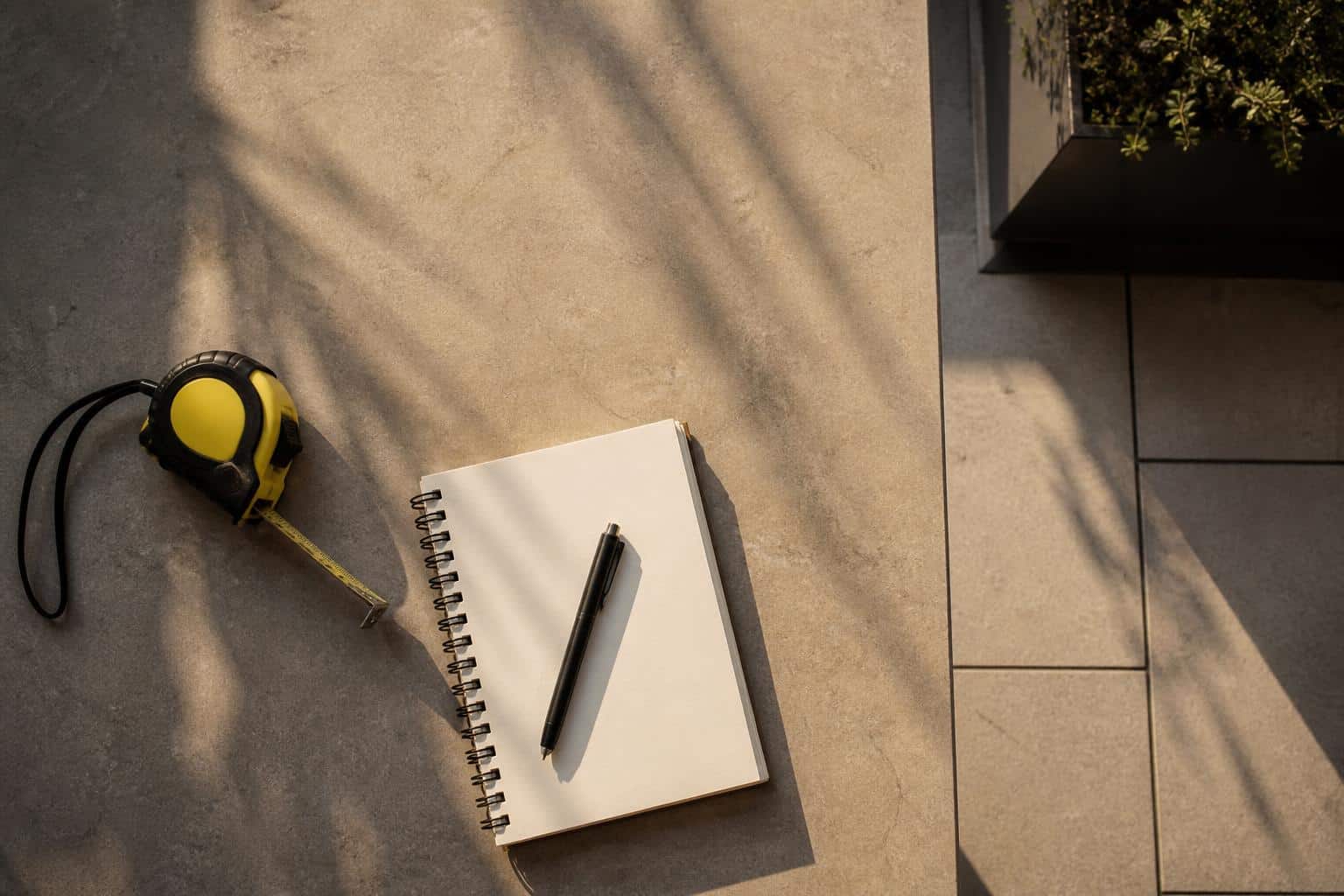 Patio layout flat-lay with tape measure and notepad, no readable text