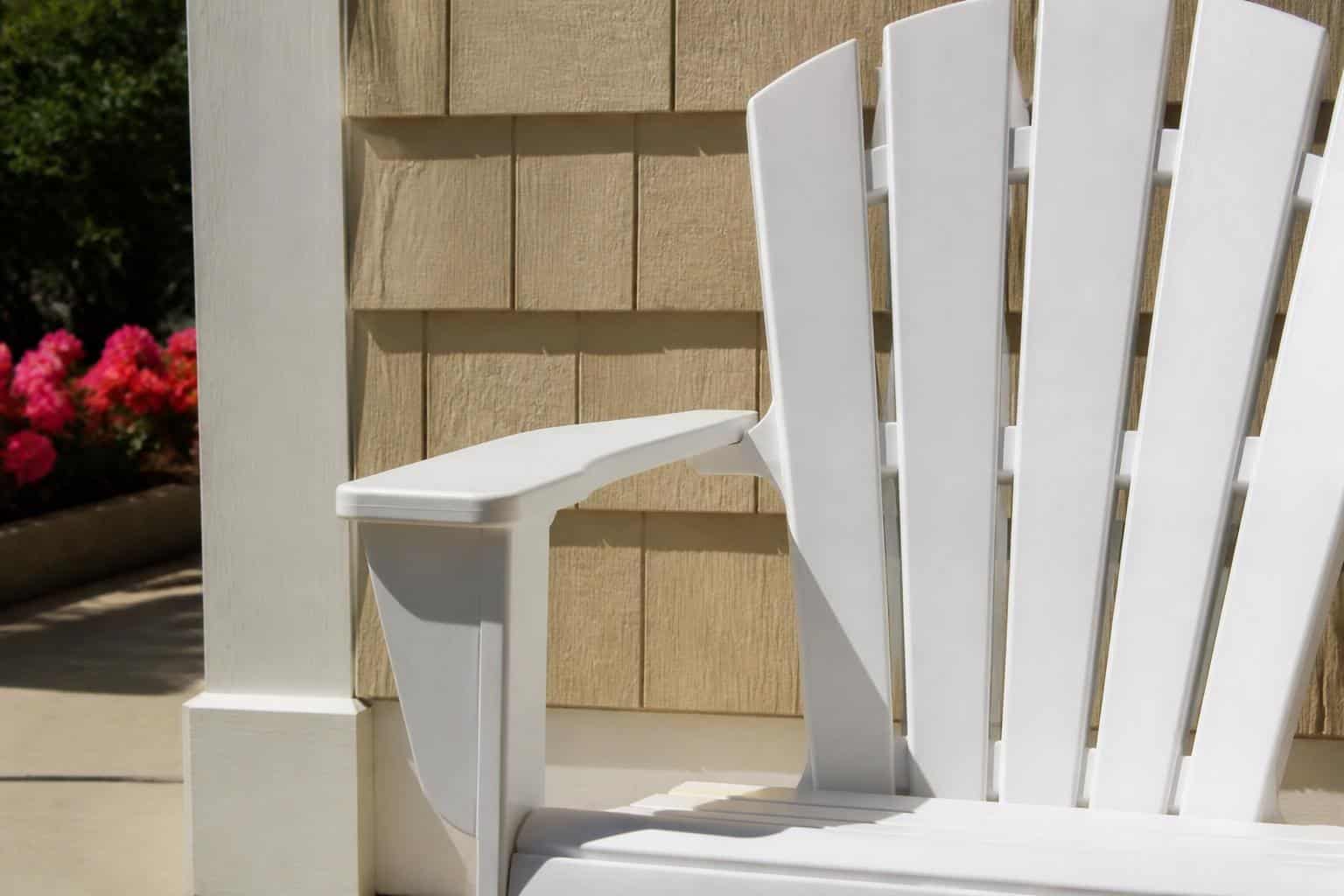 Close-up of a bright white plastic Adirondack chair armrest and wide back slats