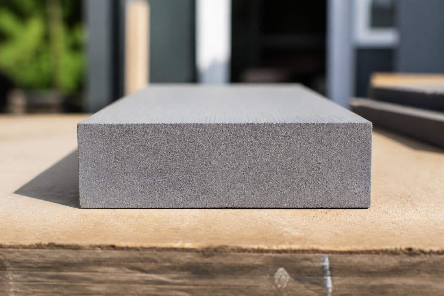 End-on cross-section view of a single solid HDPE poly lumber board showing a uniform solid plastic core all the way through, resting on a workbench