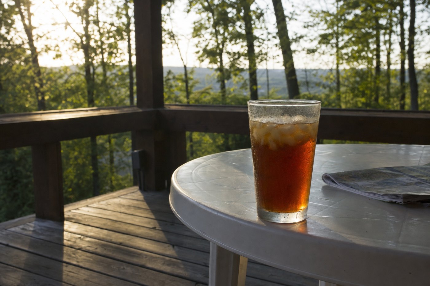 Round white side table with a drink and magazine on a porch