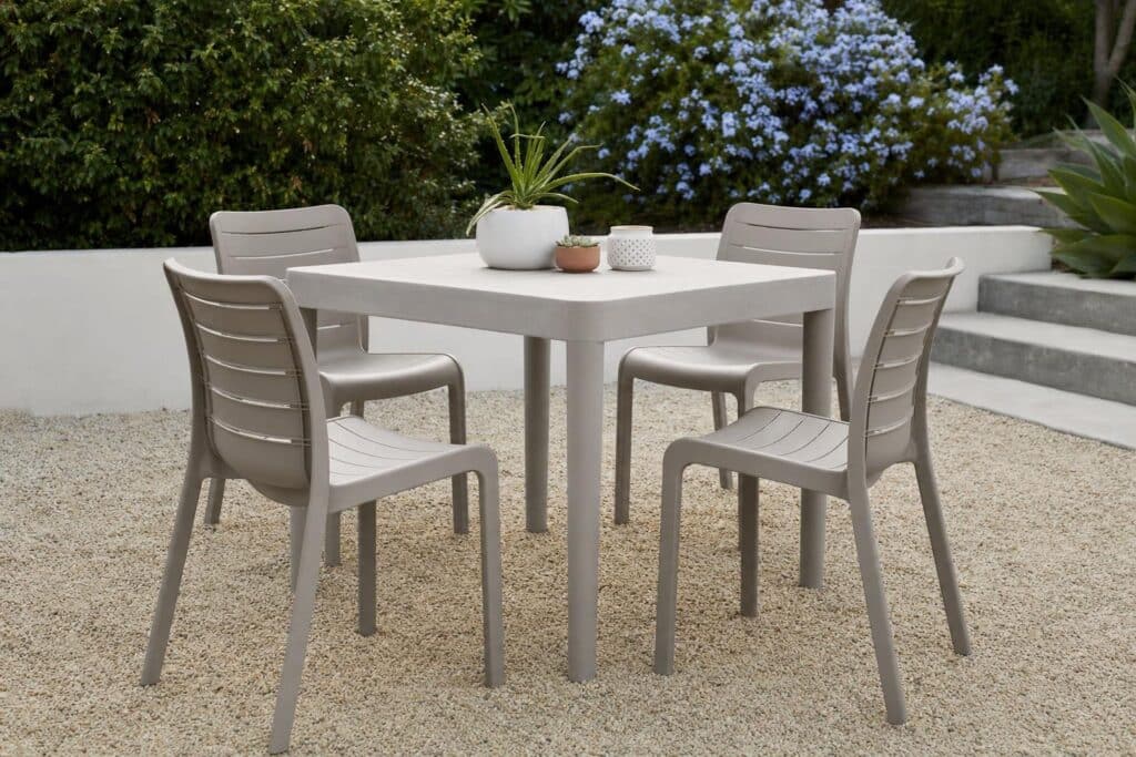 Four outdoor polymer dining chairs spaced around a patio table.