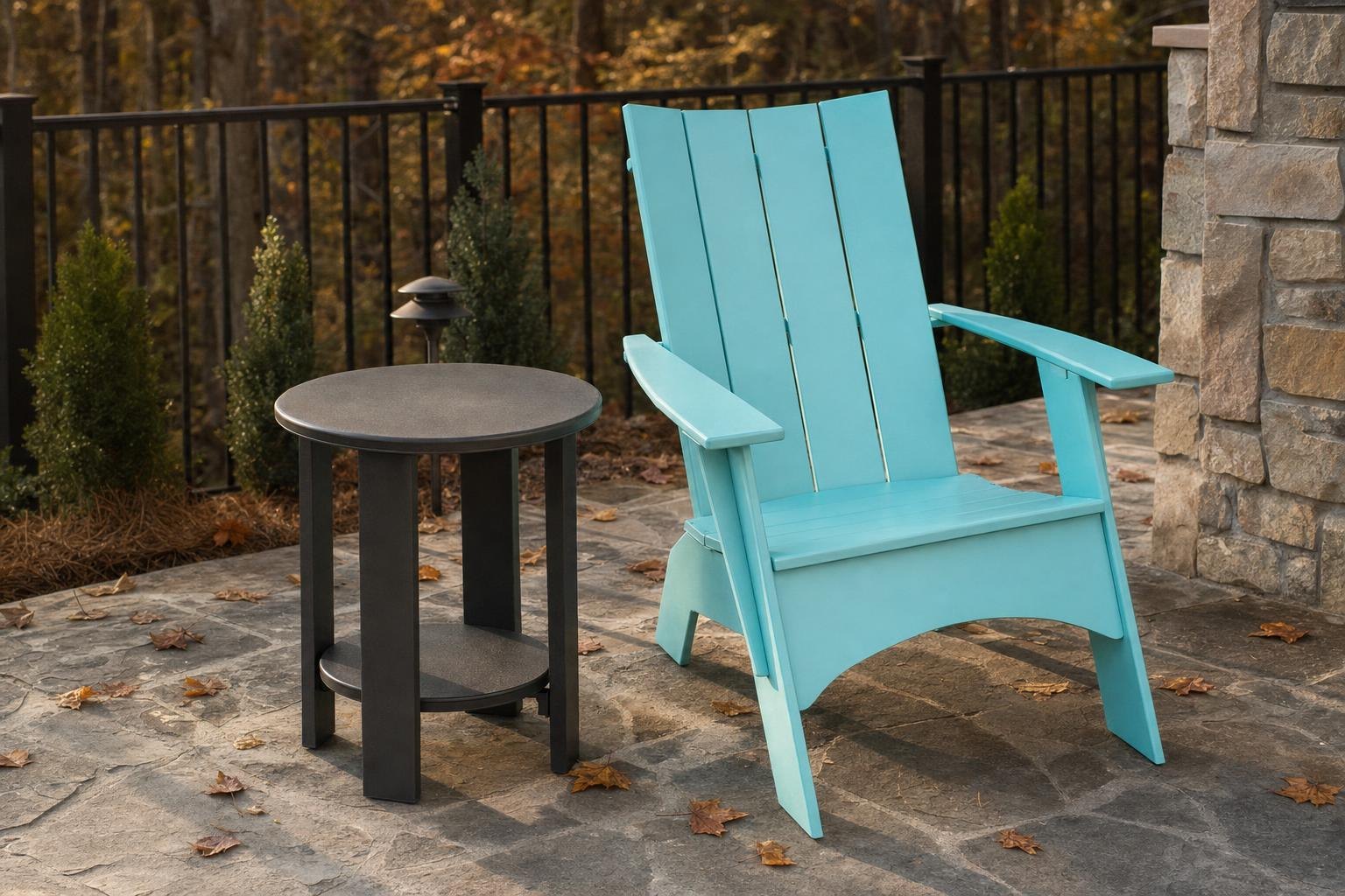 A seafoam Adirondack chair beside a round charcoal end table on a stone patio in autumn