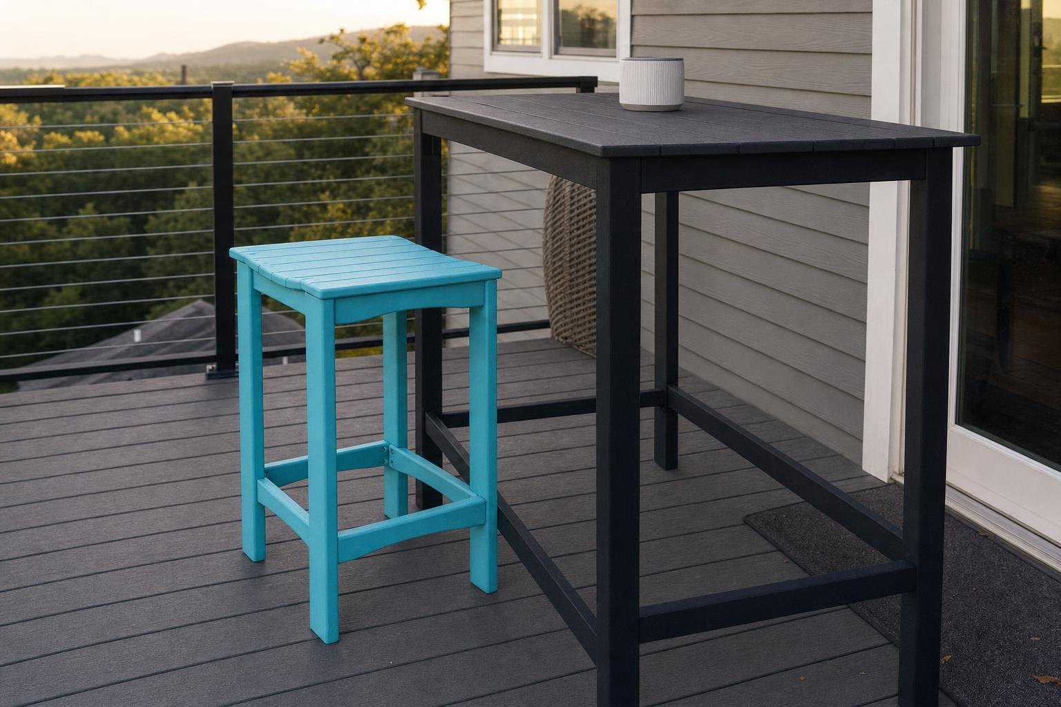 A seafoam counter height stool beside a tall dark outdoor bar table on a deck