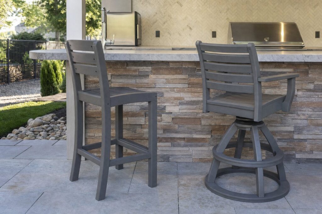 A swivel-style and a stationary outdoor counter stool beside a patio island.