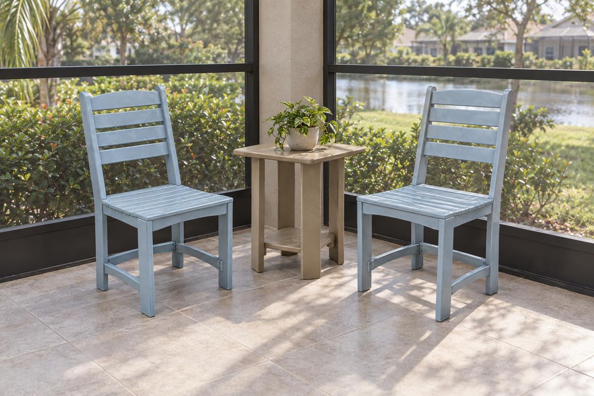 Two armless cafe chairs and a Weatherwood square end table in the corner of a screened lanai with a clear tile walkway